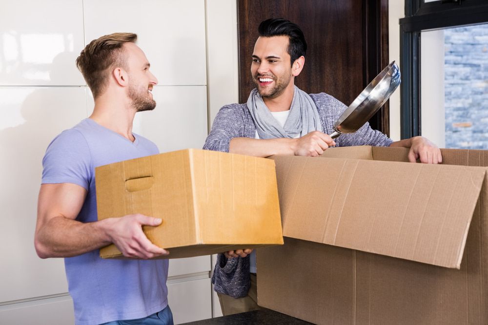 Two Men Are Carrying Cardboard Boxes Into A New Home — Newcastle Moving & Storage in Rutherford, NSW