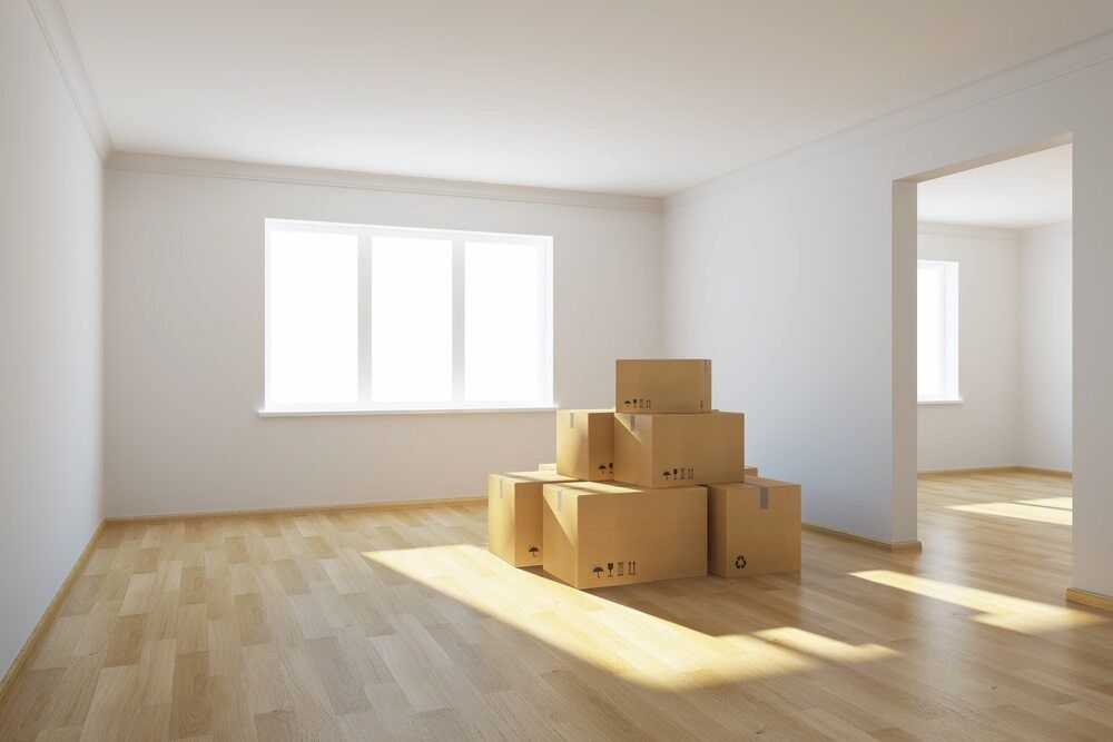 An Empty Room With A Stack Of Cardboard Boxes On The Floor — Newcastle Moving & Storage in Woy Woy, NSW