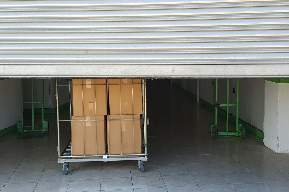 A Cart Filled With Cardboard Boxes Is Sitting Under A Garage Door — Newcastle Moving & Storage in Salt Ash, NSW