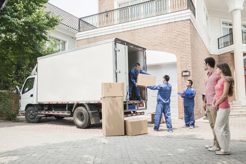 A Family Is Standing In Front Of A Moving Truck — Newcastle Moving & Storage in Gosford, NSW