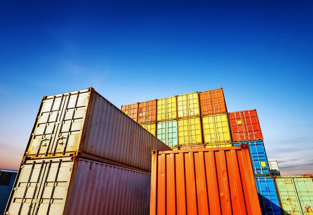 A Stack Of Colourful Shipping Containers Against A Blue Sky — Newcastle Moving & Storage in Salt Ash, NSW