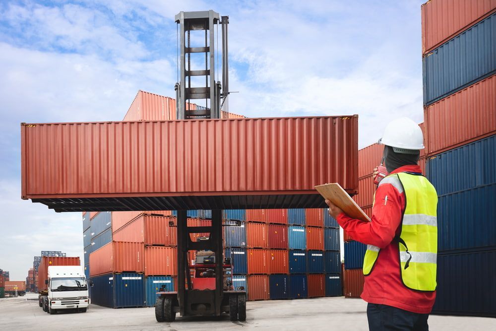A Man Is Standing In Front Of A Forklift In A Warehouse — Newcastle Moving & Storage in Salt Ash, NSW
