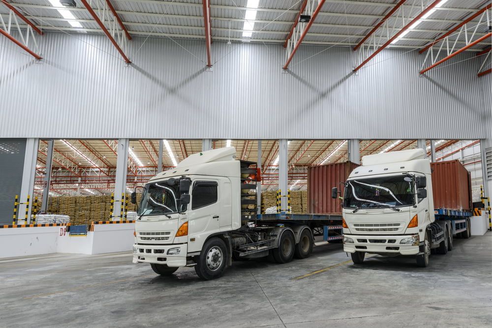 Two Trucks Are Parked In A Large Warehouse — Newcastle Moving & Storage in Salt Ash, NSW