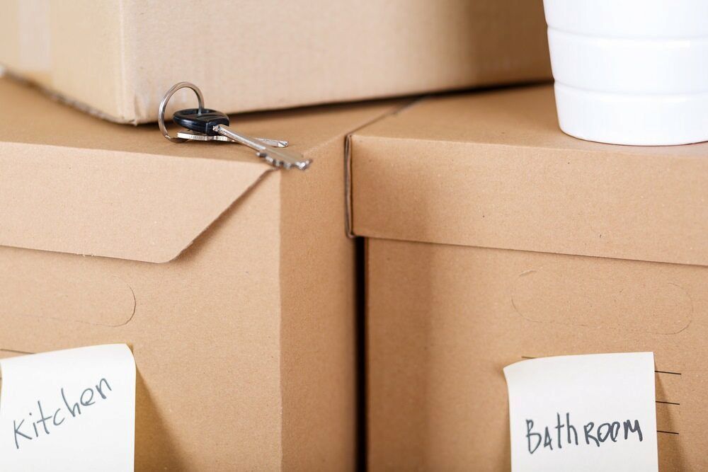 A Stack Of Cardboard Boxes With Labels For Kitchen And Bathroom — Newcastle Moving & Storage in Rutherford, NSW