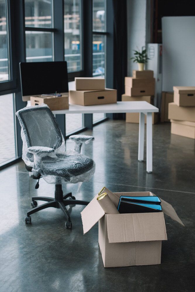 An Office With Boxes On The Floor And A Chair On A Desk — Newcastle Moving & Storage in Wallsend, NSW