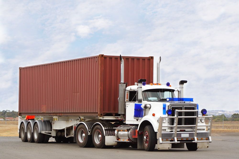 A White Semi Truck With A Red Container On The Back — Newcastle Moving & Storage in Salt Ash, NSW