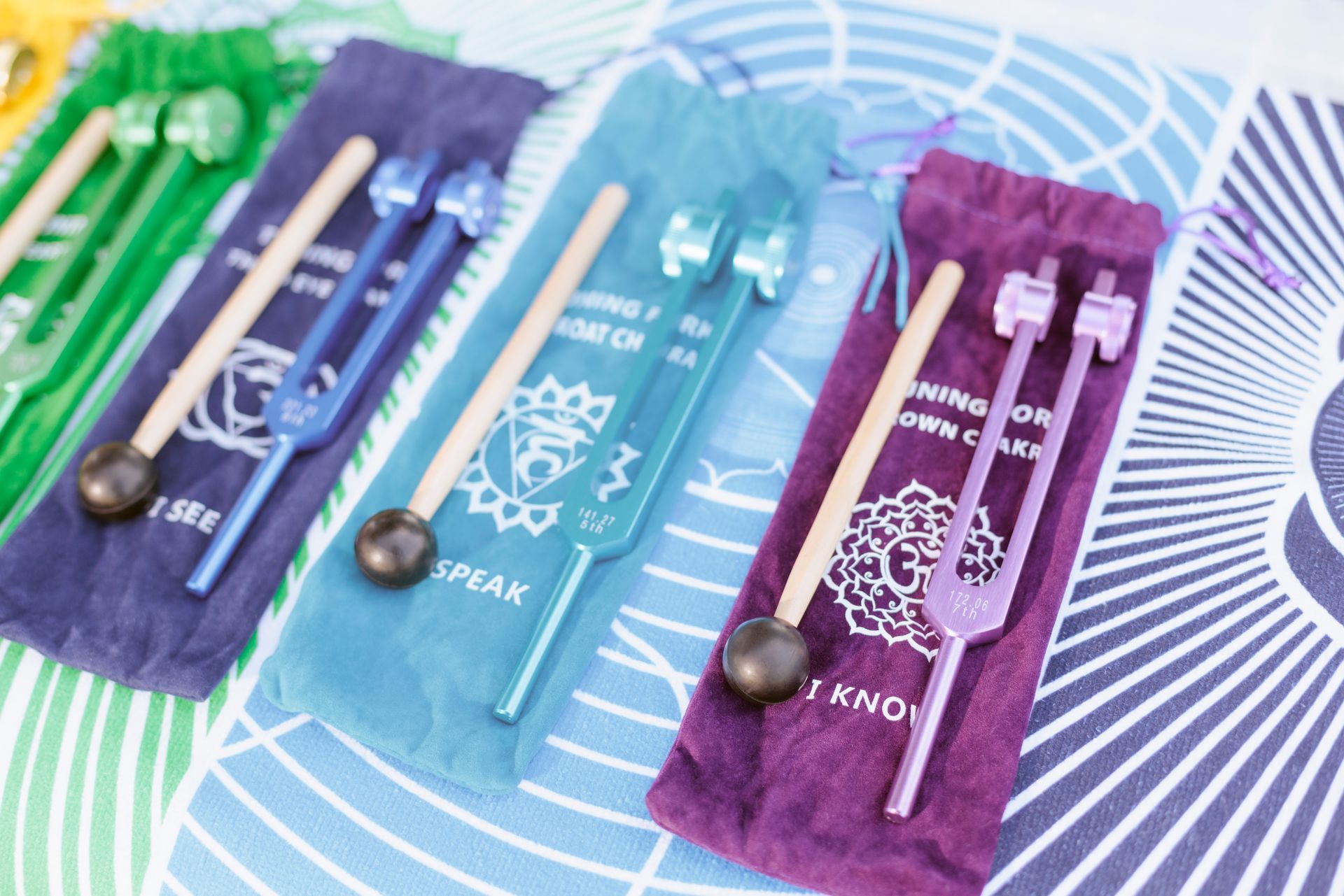 Person holding a singing bowl and mallet, with candles, crystals, and yoga mat; setting is calm.