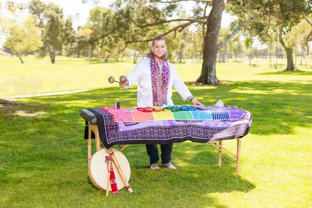 Person playing crystal singing bowls on a rug in a sunlit room.