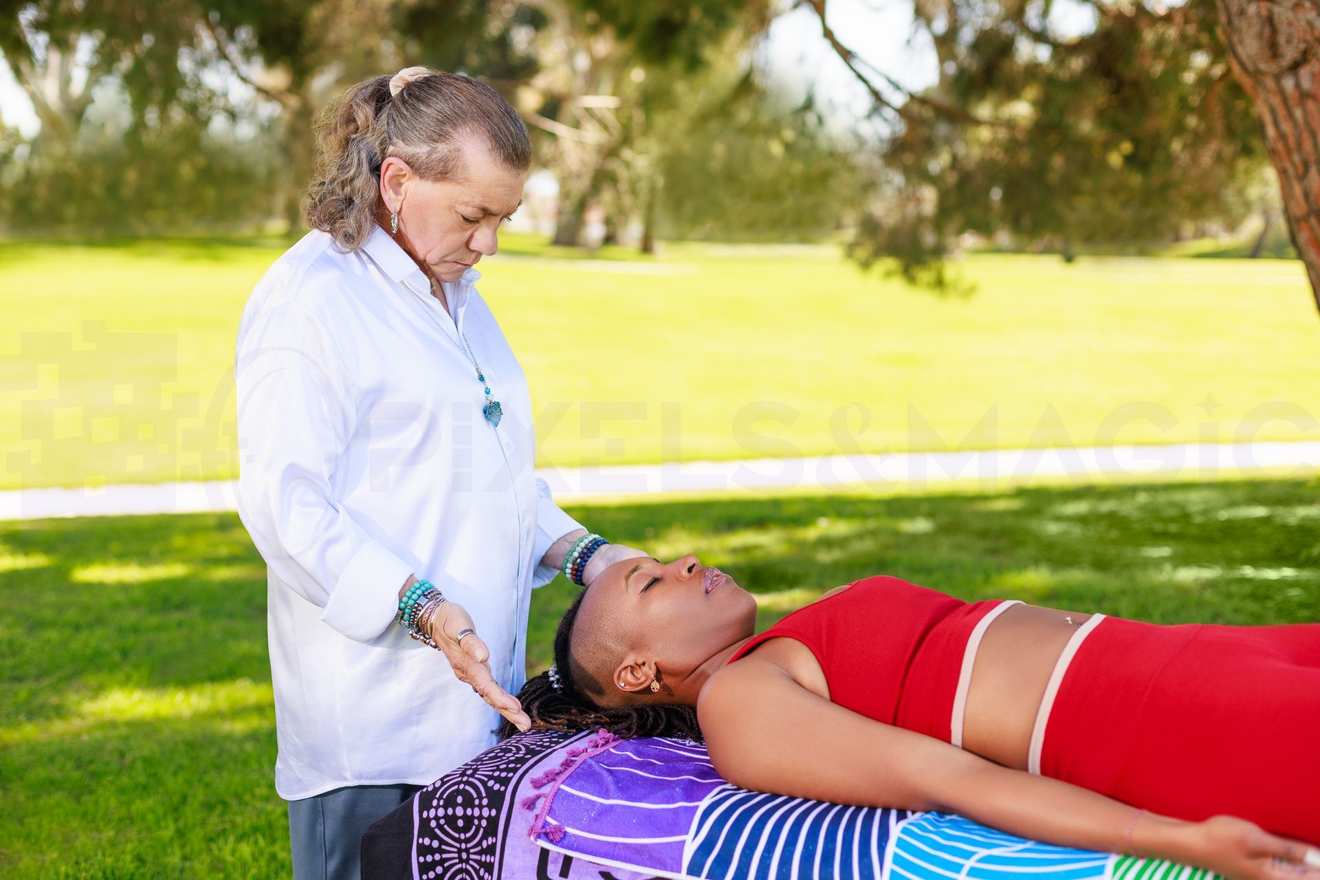 Woman receiving reiki treatment; therapist's hands over her forehead. Eyes closed. Indoor setting.