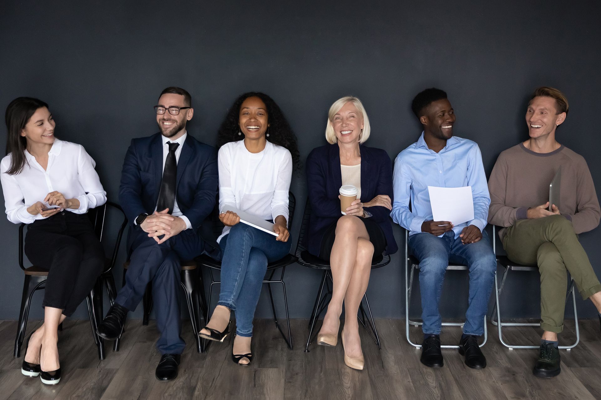 A group of people are sitting in chairs waiting for a job interview.
