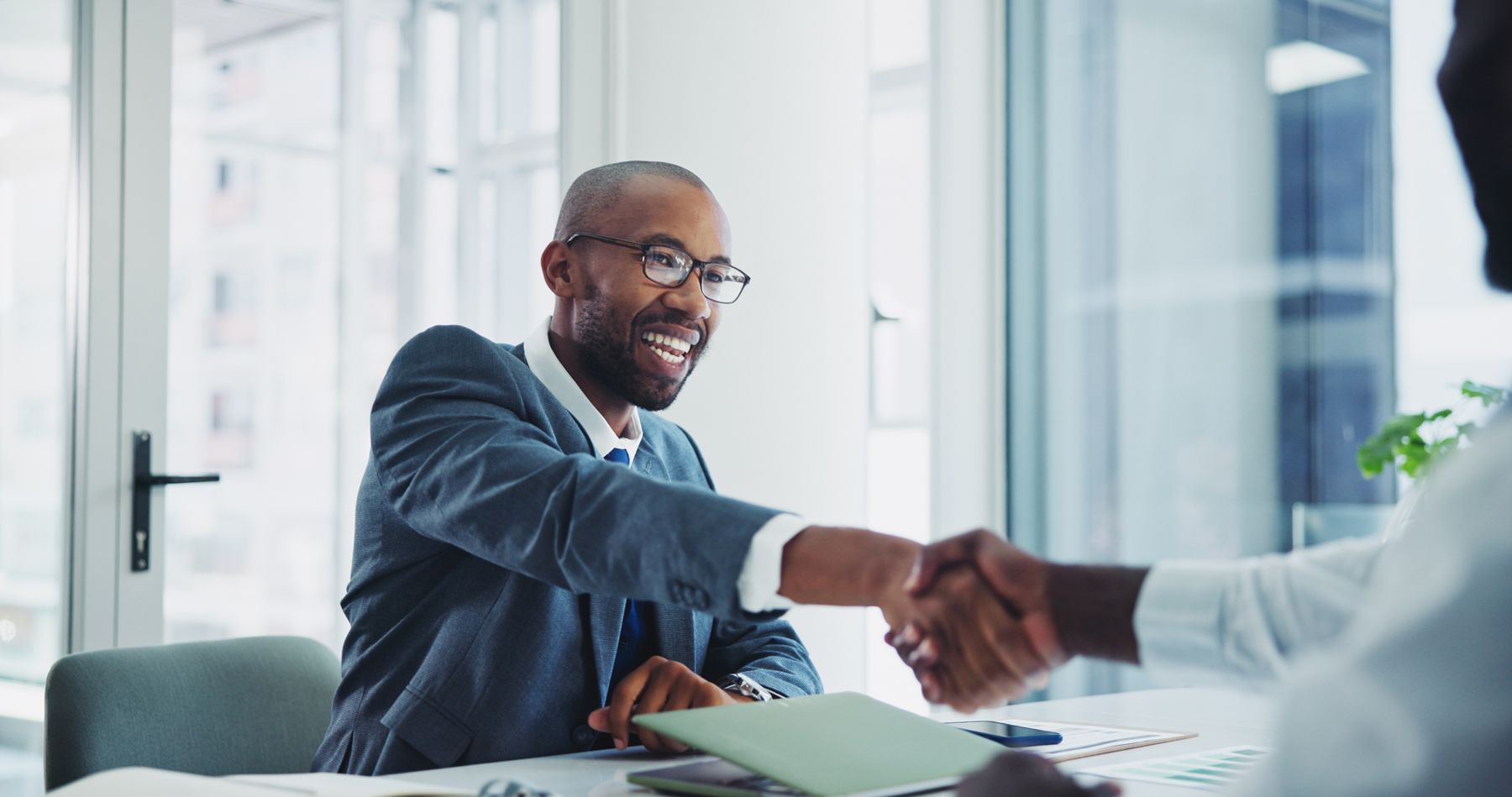 A man in a suit and tie is shaking hands with another man.