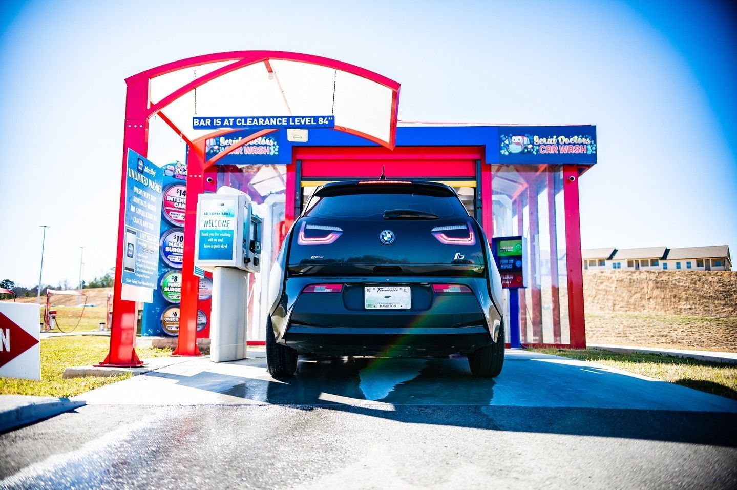 A black car is parked in front of a car wash