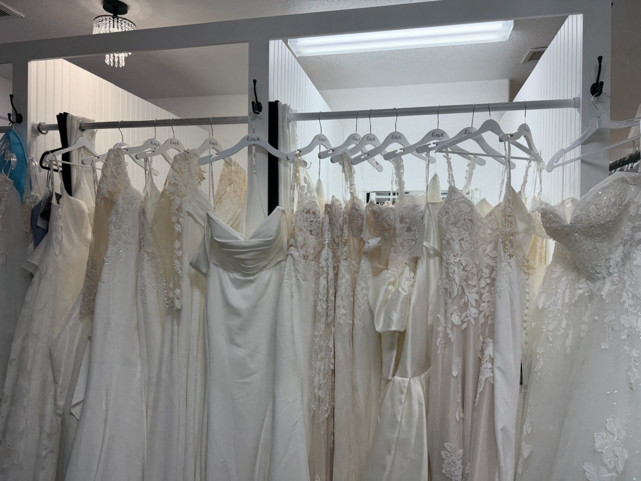 White dresses hanging on racks in a bridal shop display