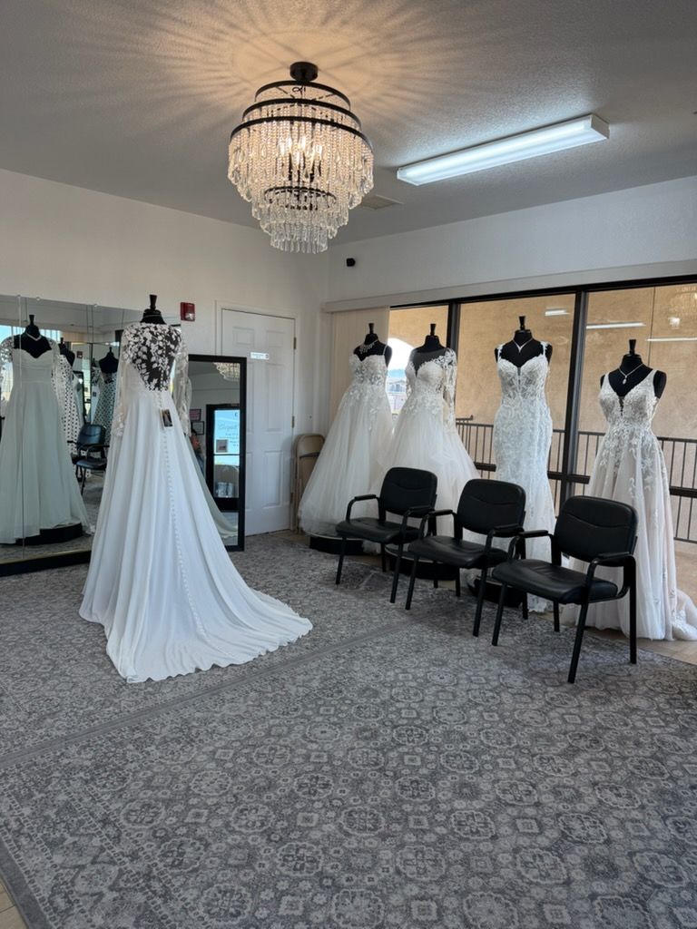 Bridal boutique with white wedding gowns on mannequins and chairs under a chandelier