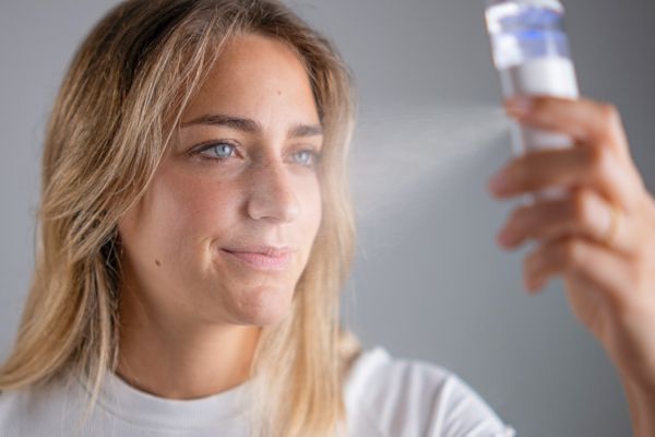 Frau benutzt Wasserstoffspray im Gesicht