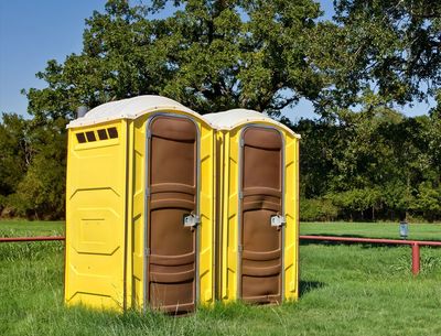 Two Yellow Portable Toilets at a Park — Kenedy, TX — Amron Pumping Services