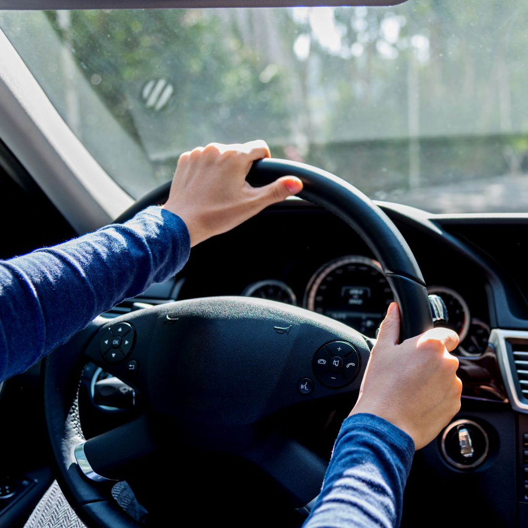 A person is holding the steering wheel of a car