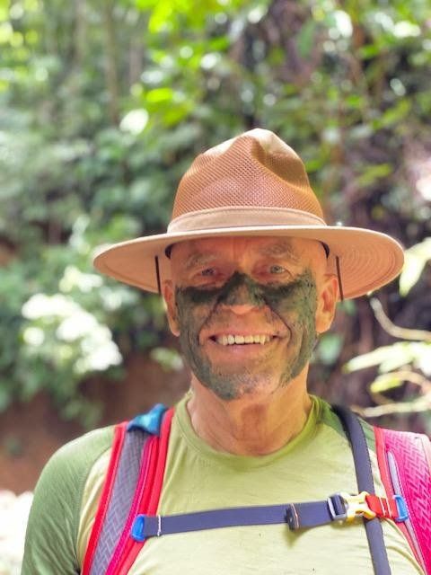 A man with green paint on his face wearing a hat