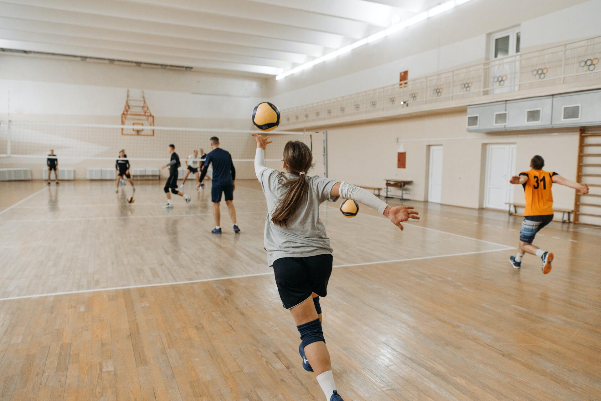 A group of people are playing volleyball in a gym.