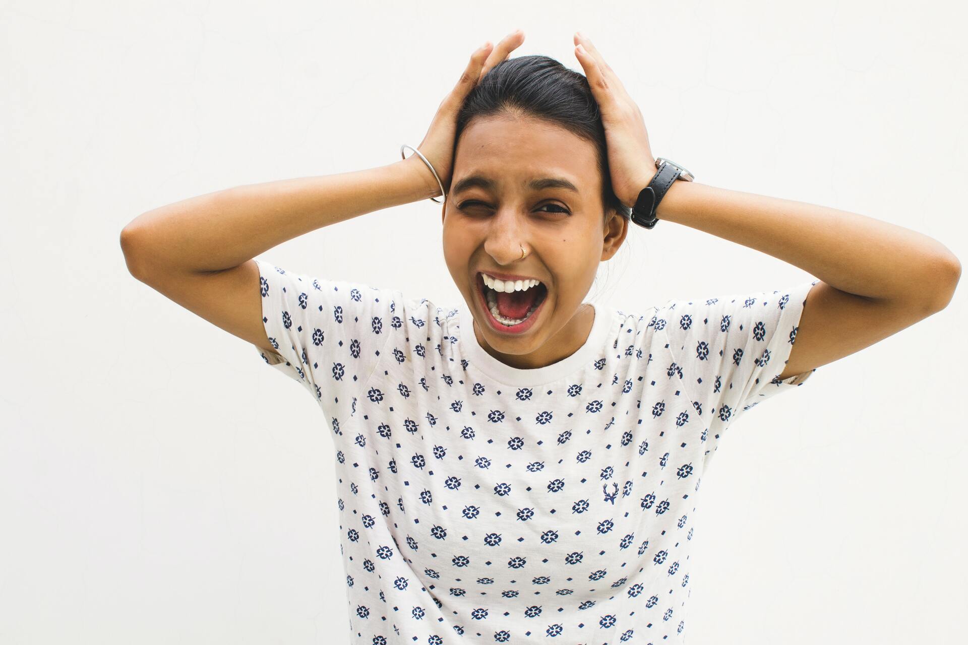 A woman is holding her head with her hands and smiling.