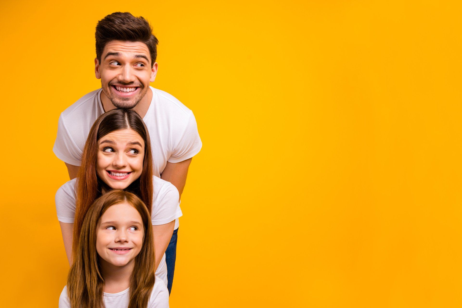 A man and two girls are standing next to each other on a yellow background.