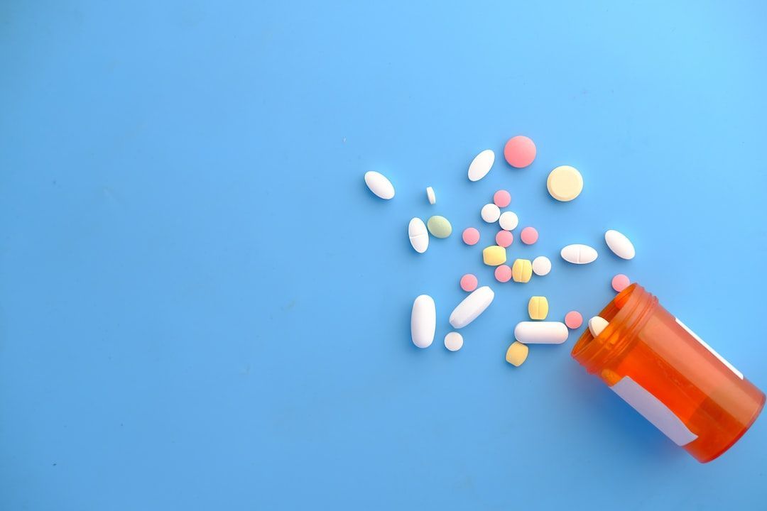 A bottle of pills is pouring out of it on a blue surface.