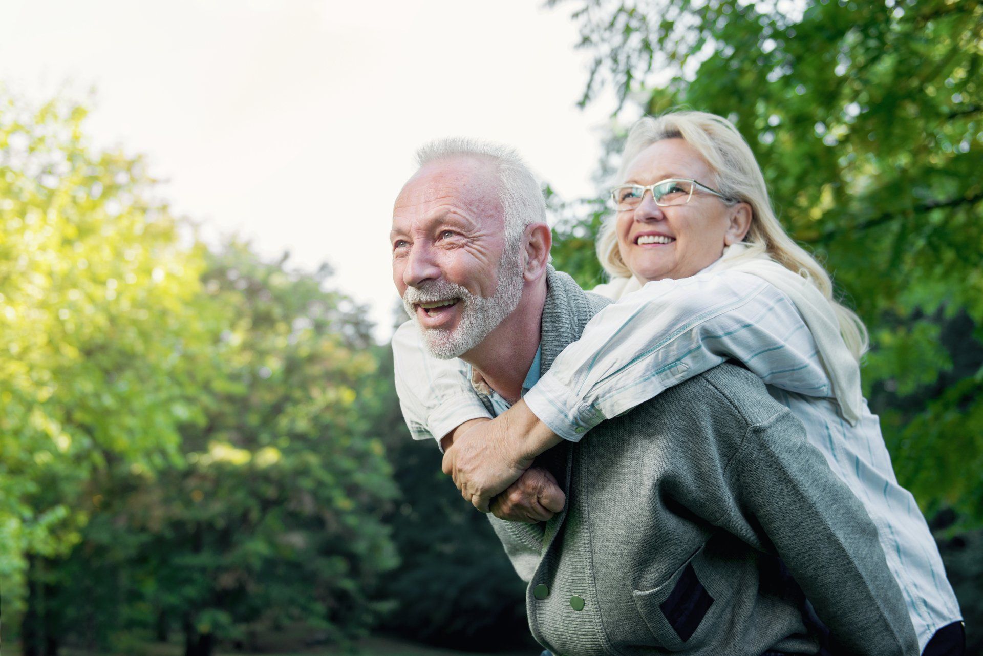 A man is giving a woman a piggyback ride in the park.