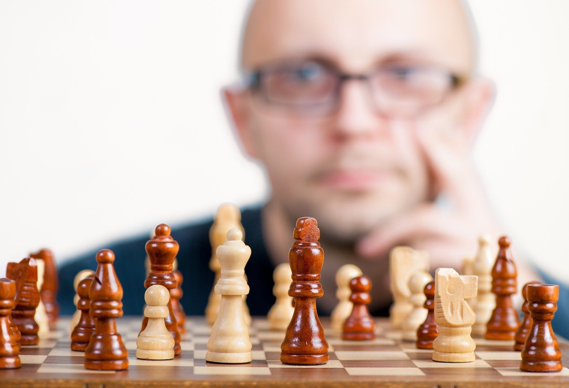 A man wearing glasses is playing a game of chess.