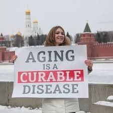 A woman is holding a sign that says `` aging is a curable disease ''.