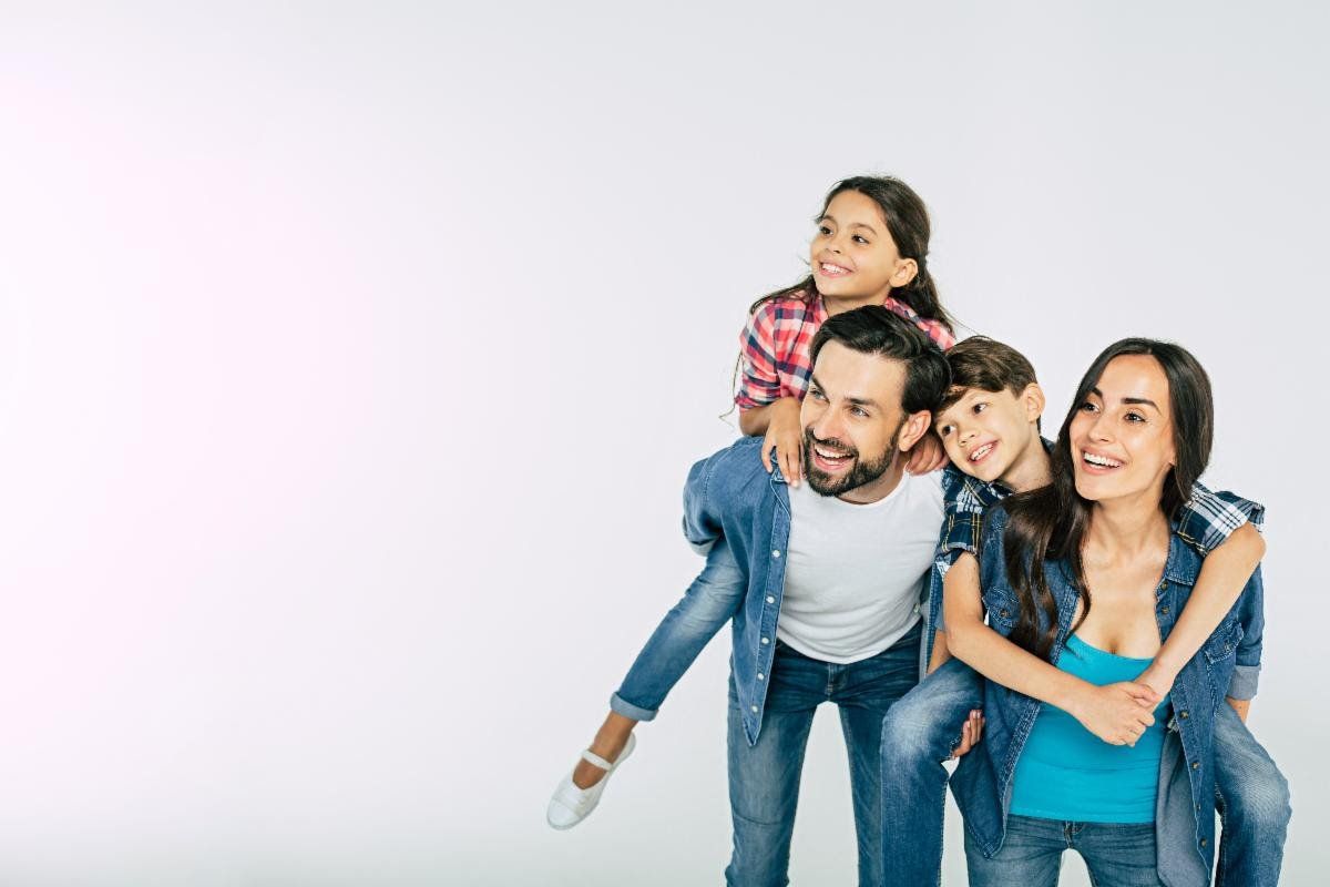 A family is posing for a picture while a woman is carrying a child on her back.