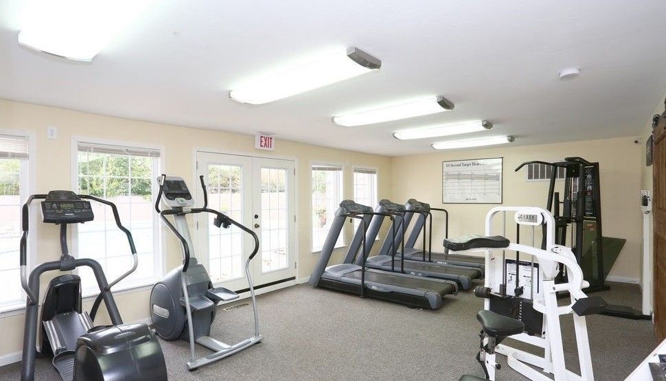 A small gym with exercise machines, including treadmills and elliptical trainers.