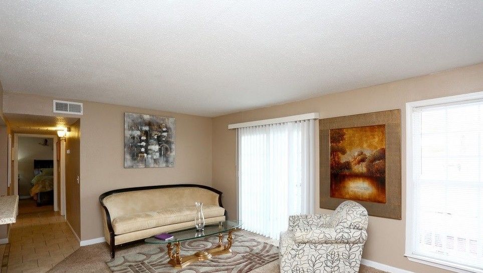 Living room with couch, chair, artwork, and a sliding glass door.