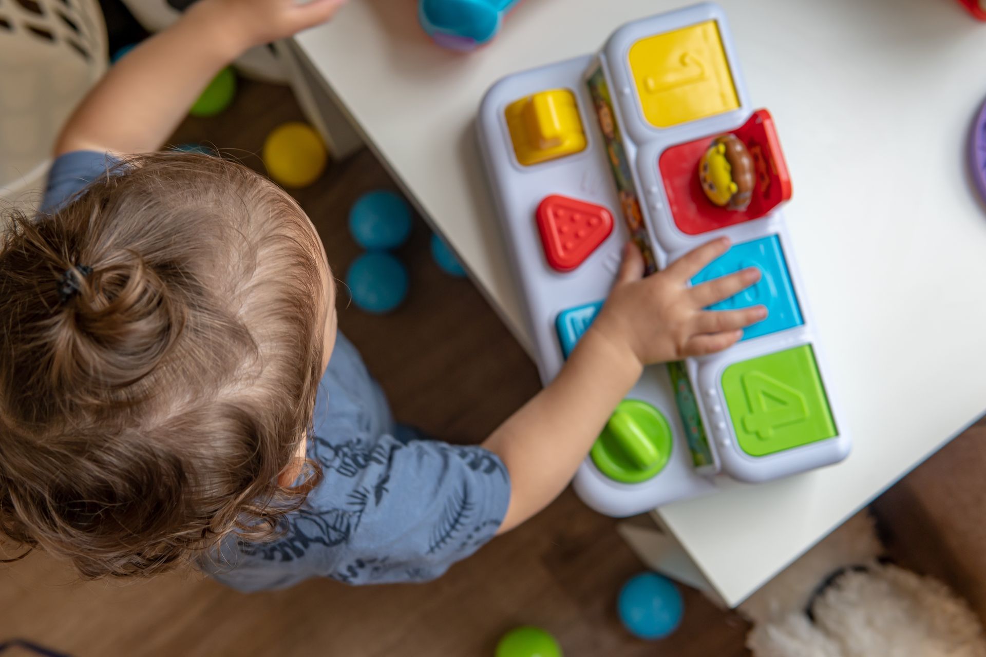 A young boy is playing with a toy on a table.