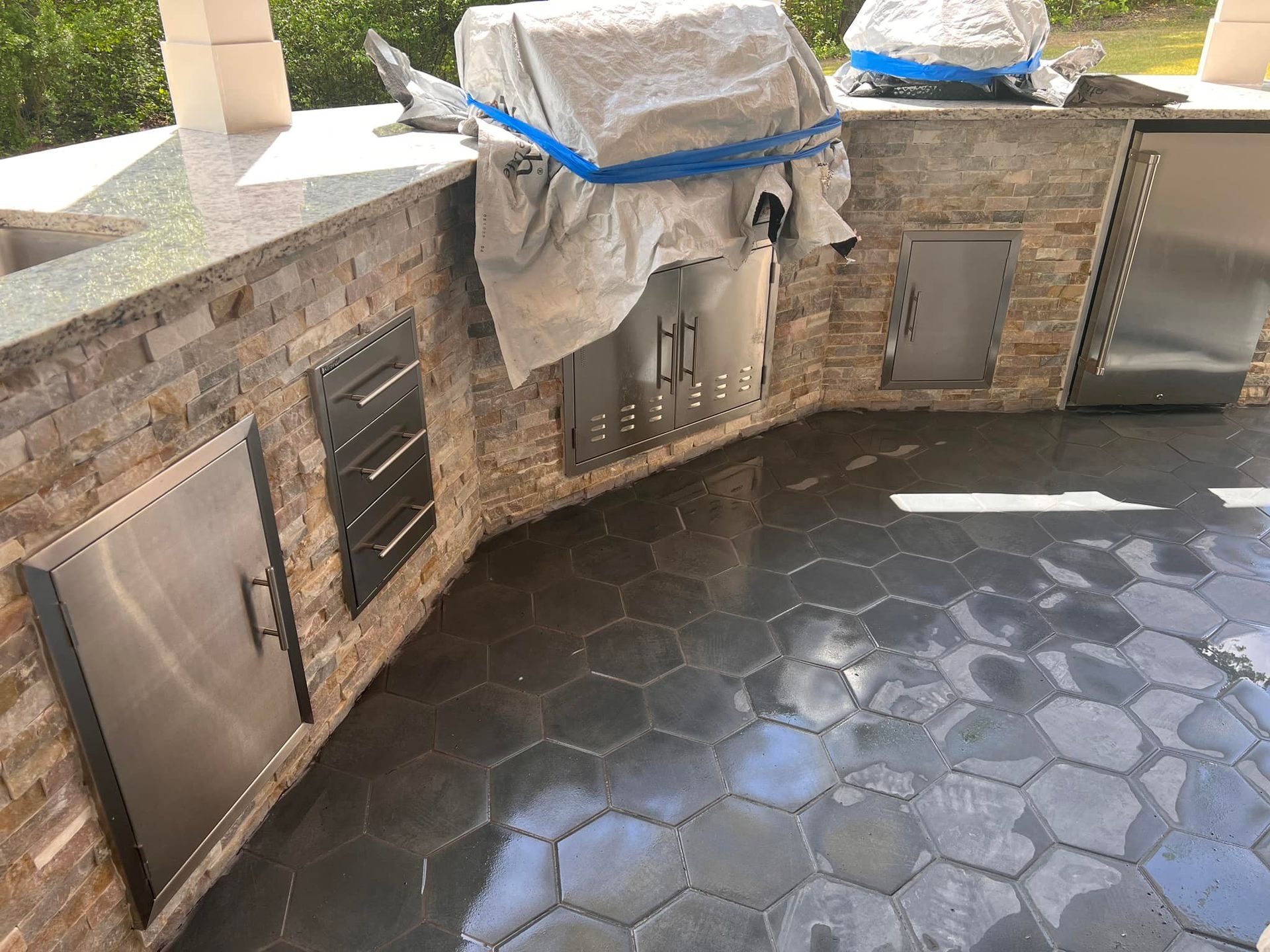 A grill is sitting on top of a brick counter in a kitchen.