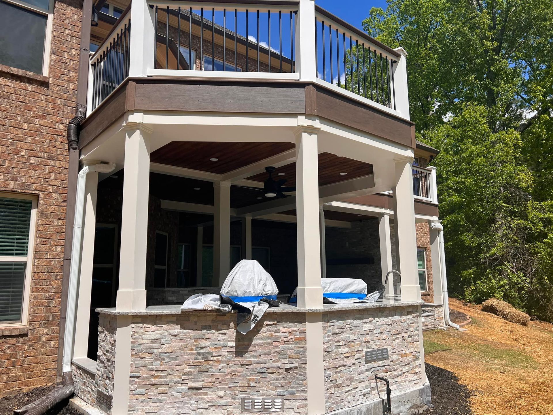 There is a large deck with a grill on it in the backyard of a house.