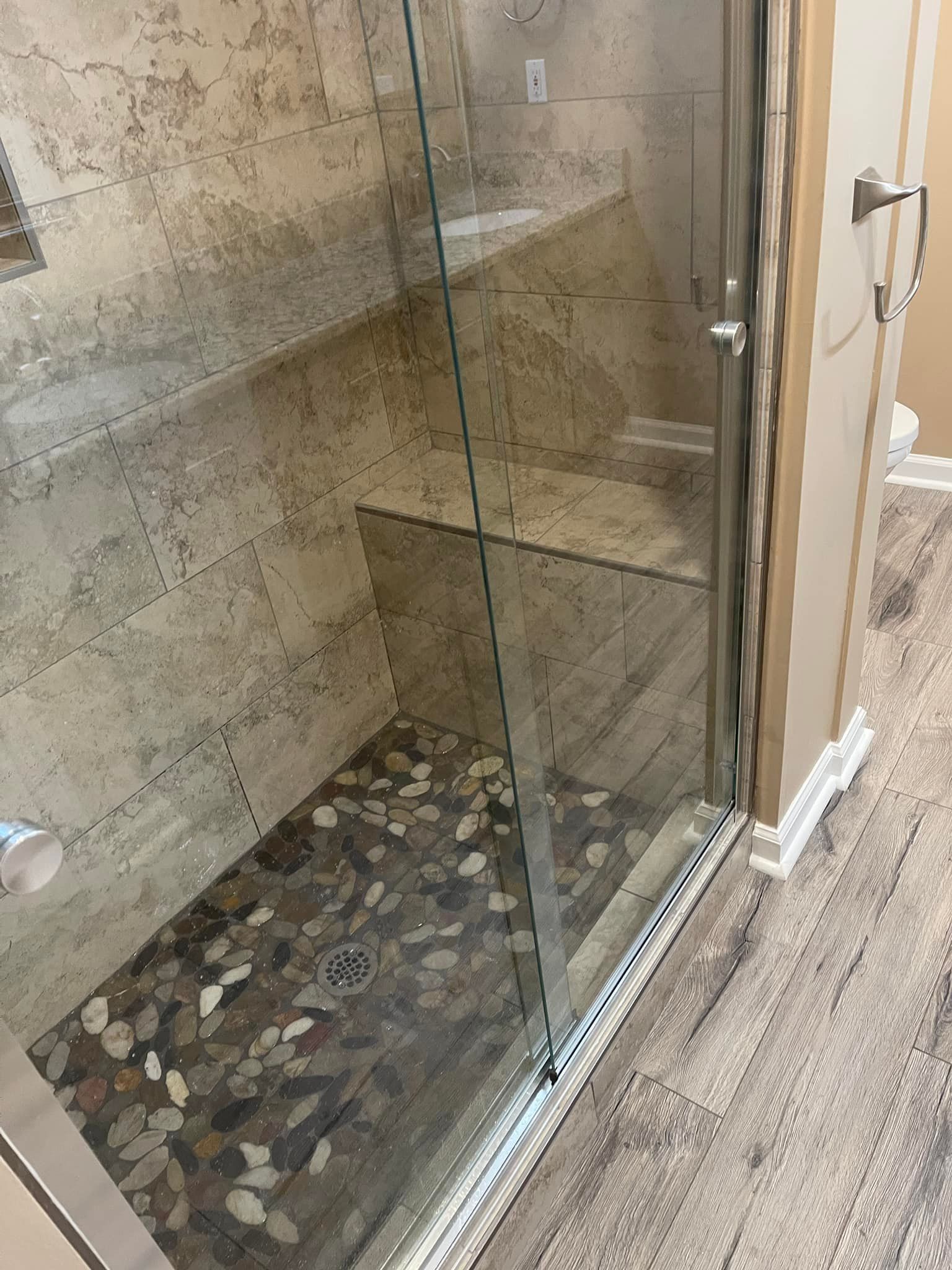 A bathroom with a walk in shower with a glass door.