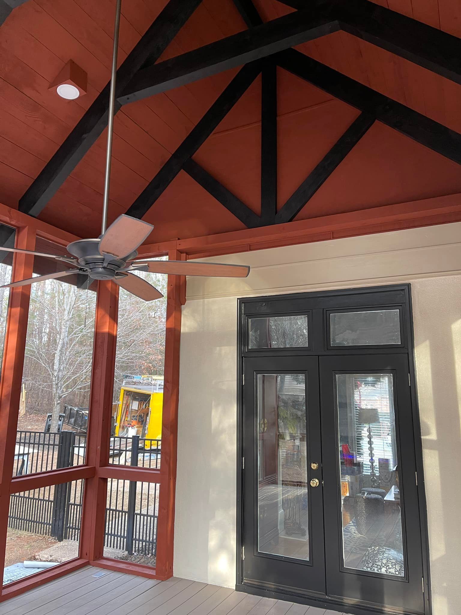 A screened in porch with a ceiling fan hanging from the ceiling.
