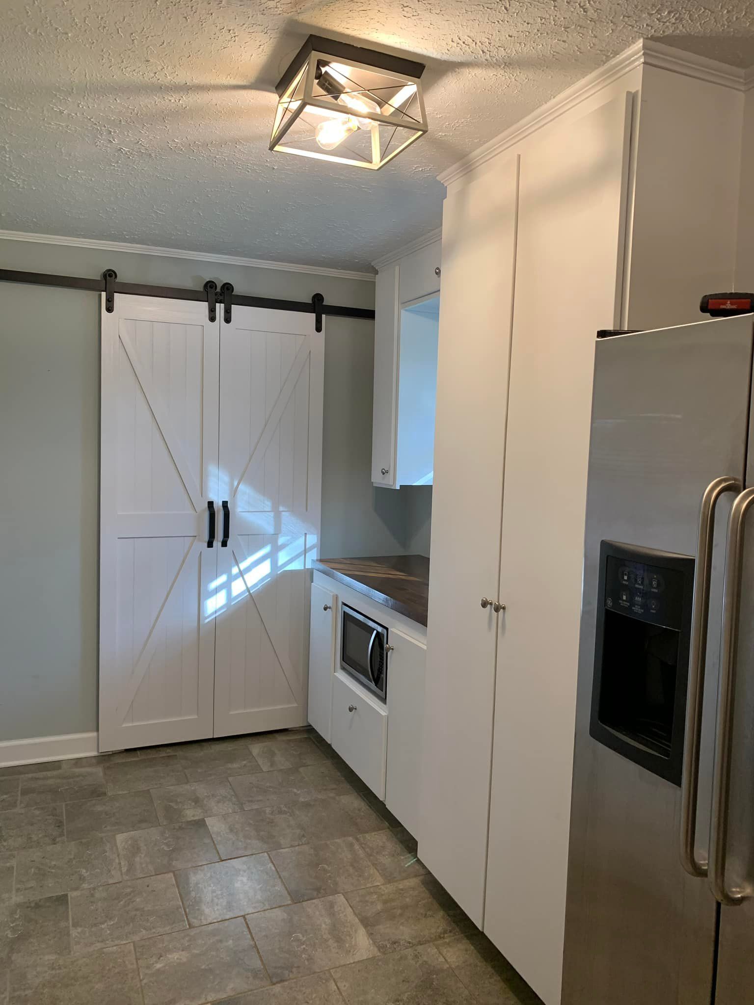 A kitchen with sliding barn doors and a stainless steel refrigerator.