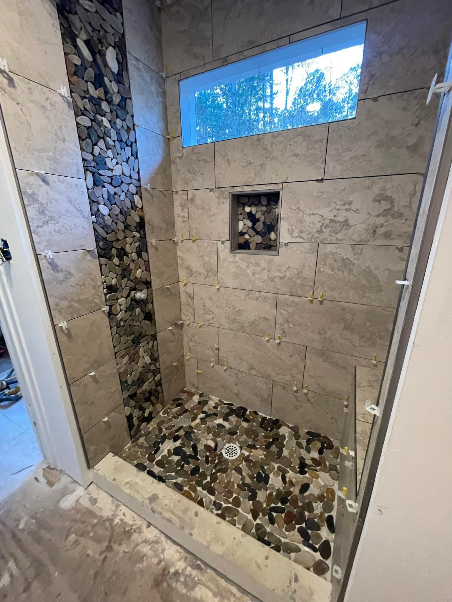 A bathroom with a walk in shower and a window.