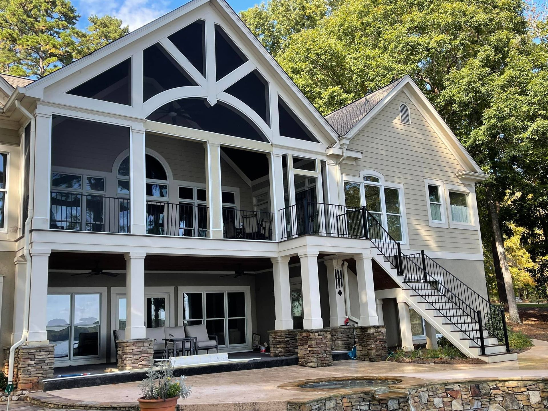 A large house with a large porch and stairs is surrounded by trees.