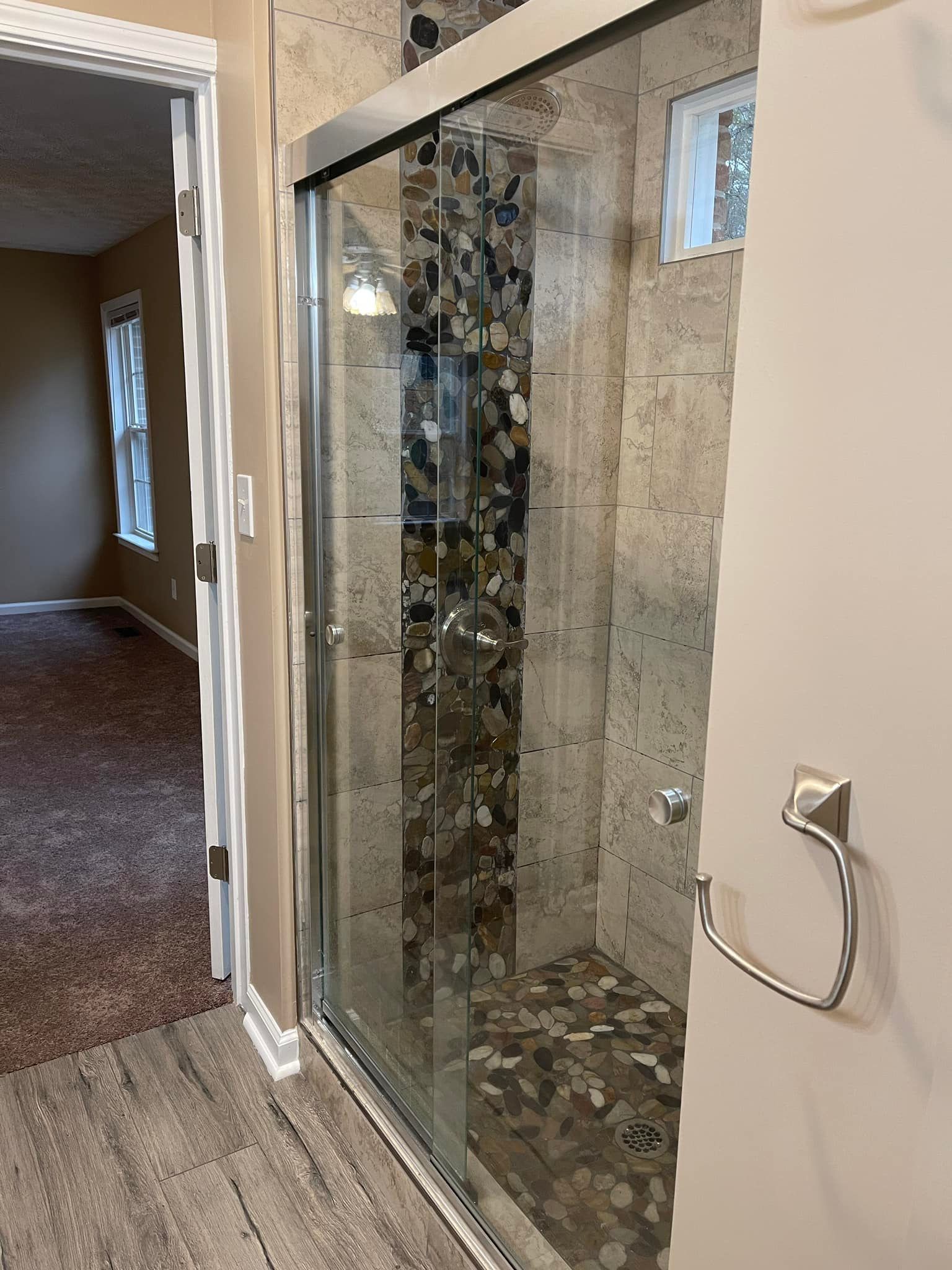 A bathroom with a sliding glass shower door and a towel rack.