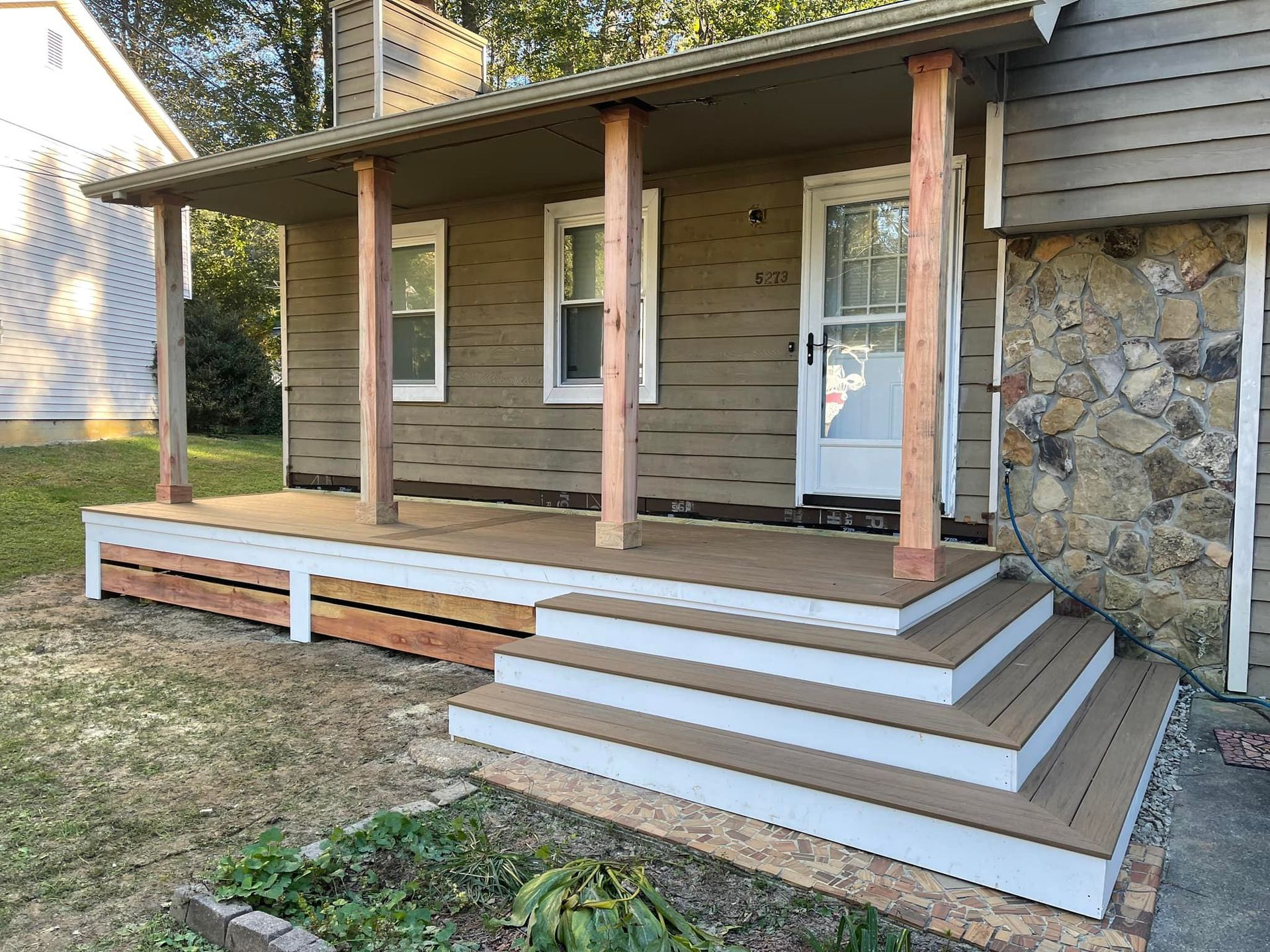 A house with a porch and stairs in front of it.