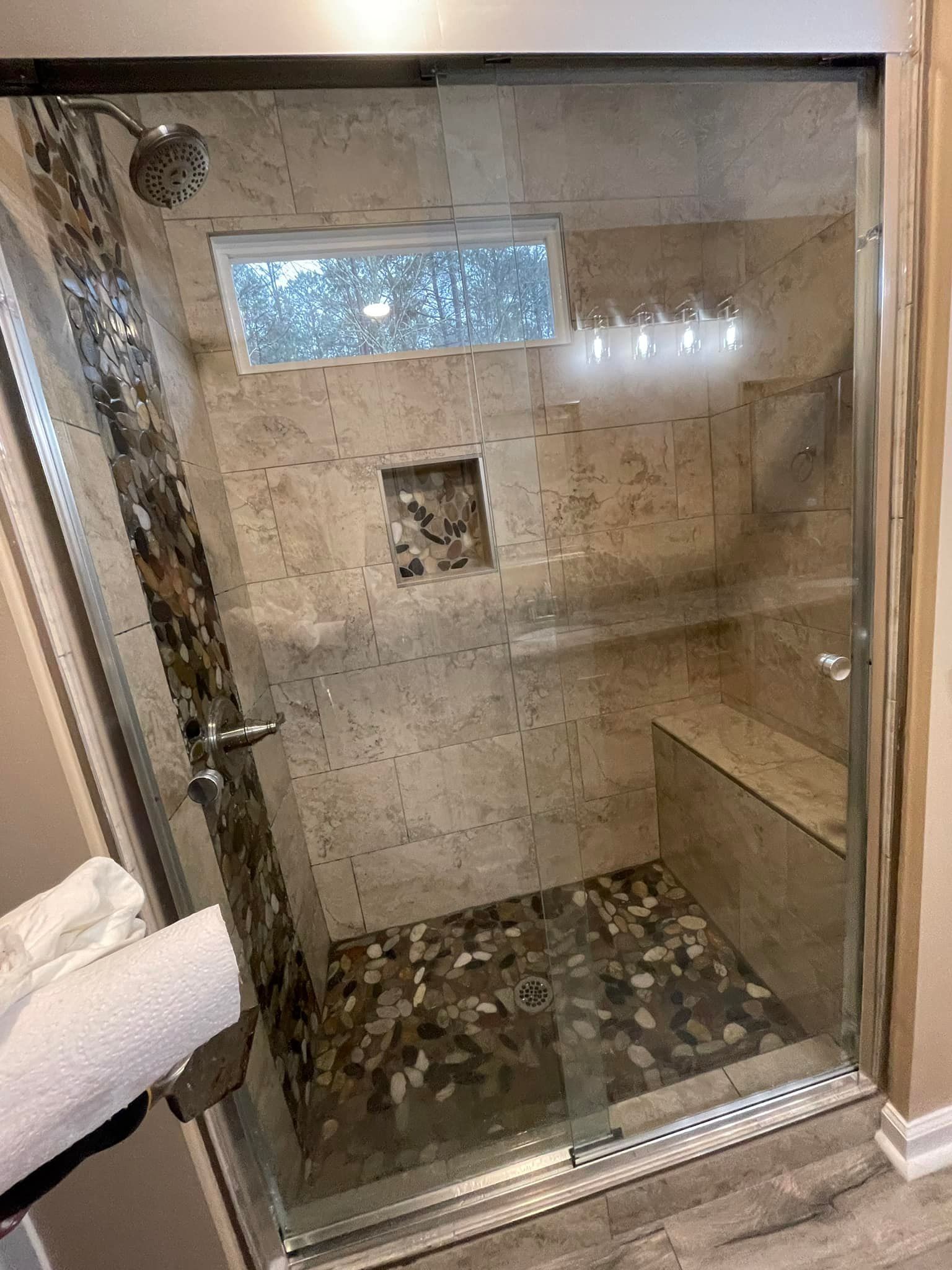 A bathroom with a walk in shower with a glass door.
