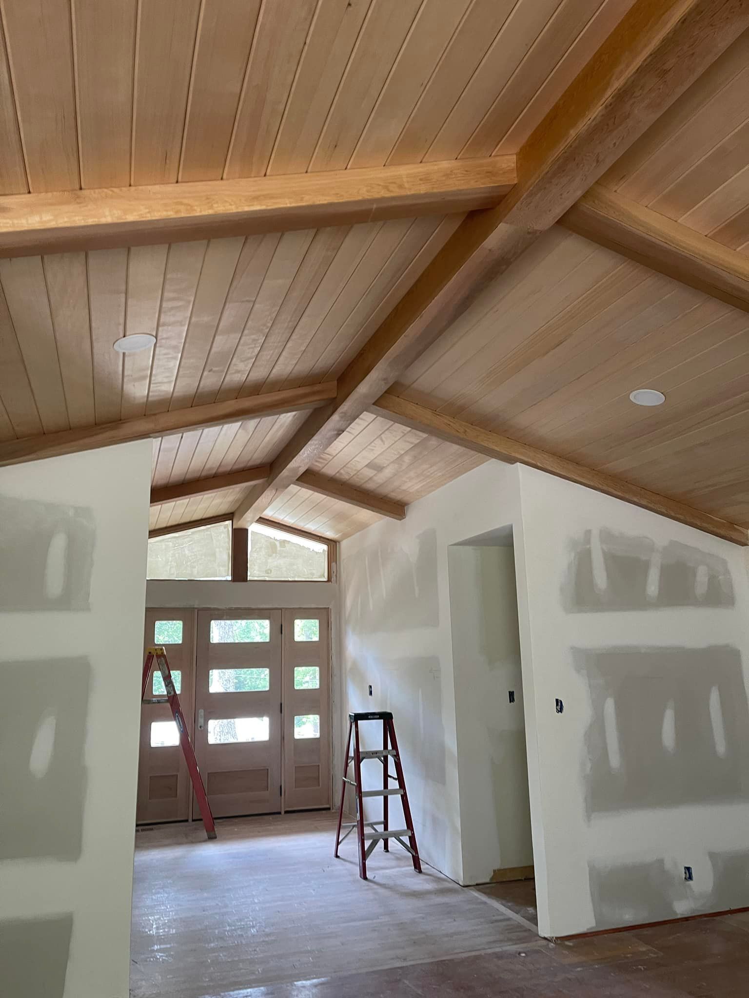 A room with a wooden ceiling and a ladder in it.