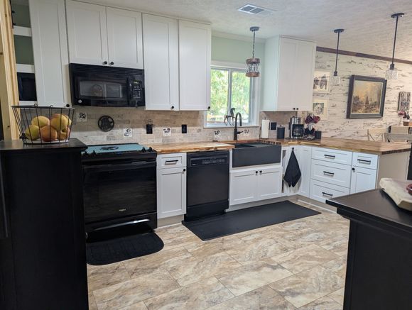 Modern kitchen with wood cabinets, stainless steel appliances, and light wood floors.