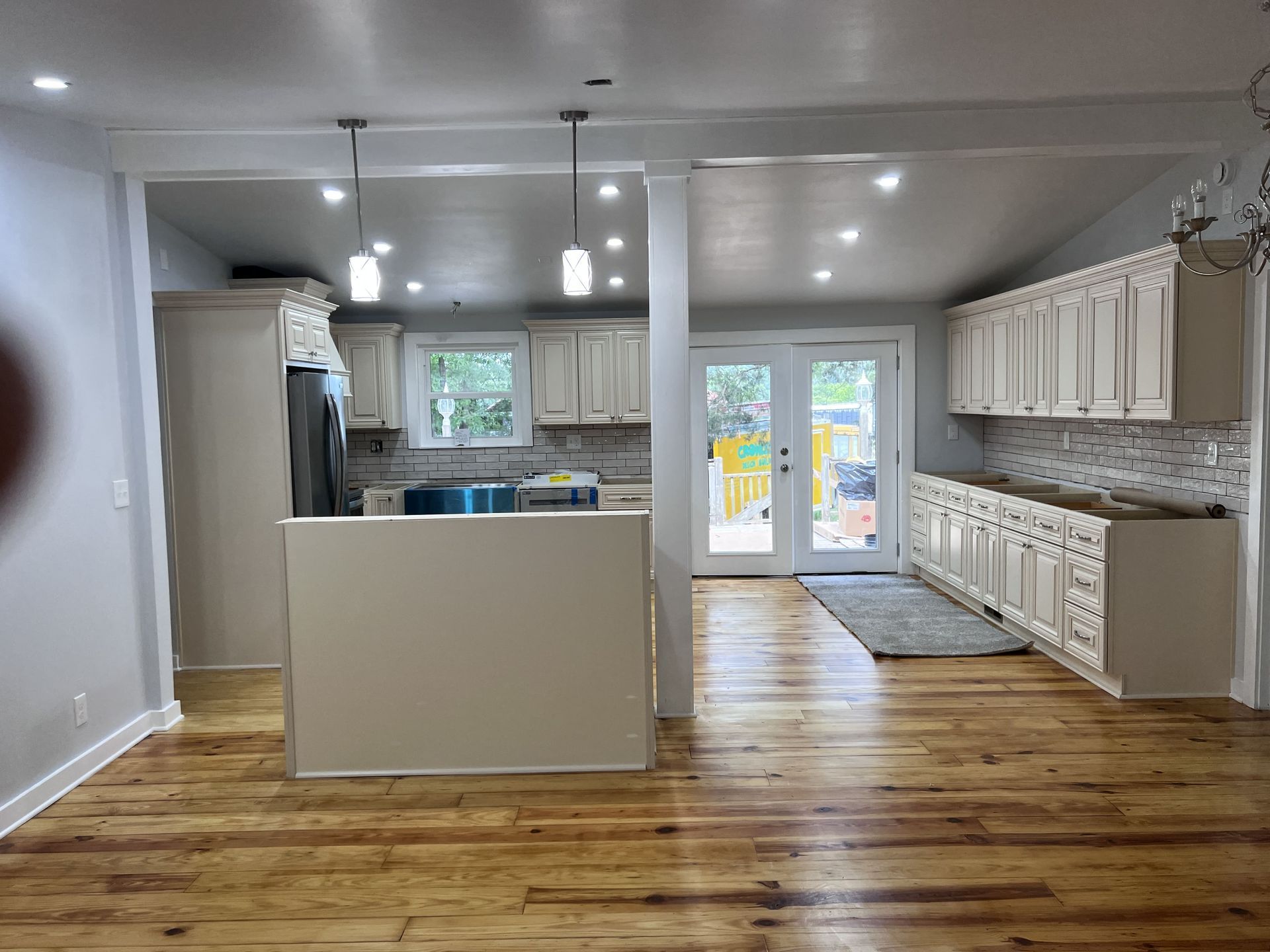Kitchen renovation with white cabinets, wood floors, and French doors to a backyard.