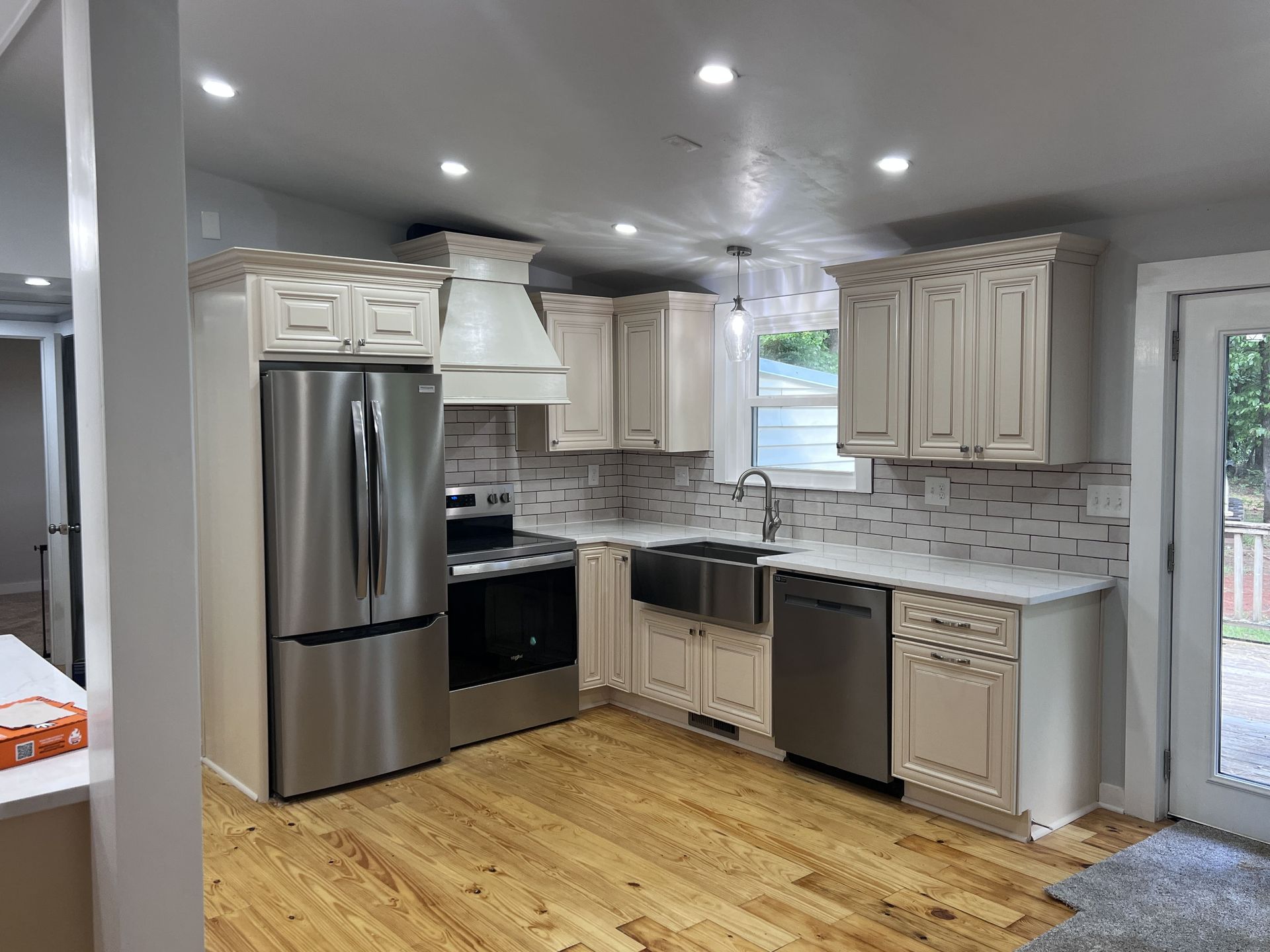 Newly renovated kitchen with stainless steel appliances, white cabinets, and light wood floors.