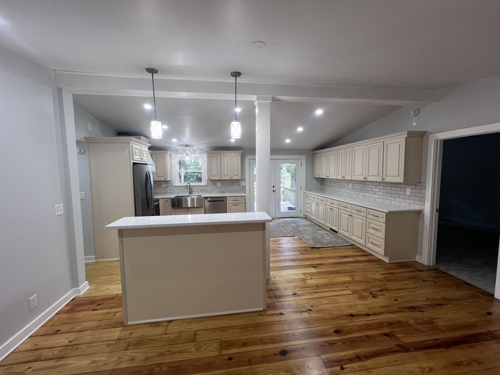 Spacious kitchen with light-colored cabinets, island, and wood flooring. Natural light streams in.