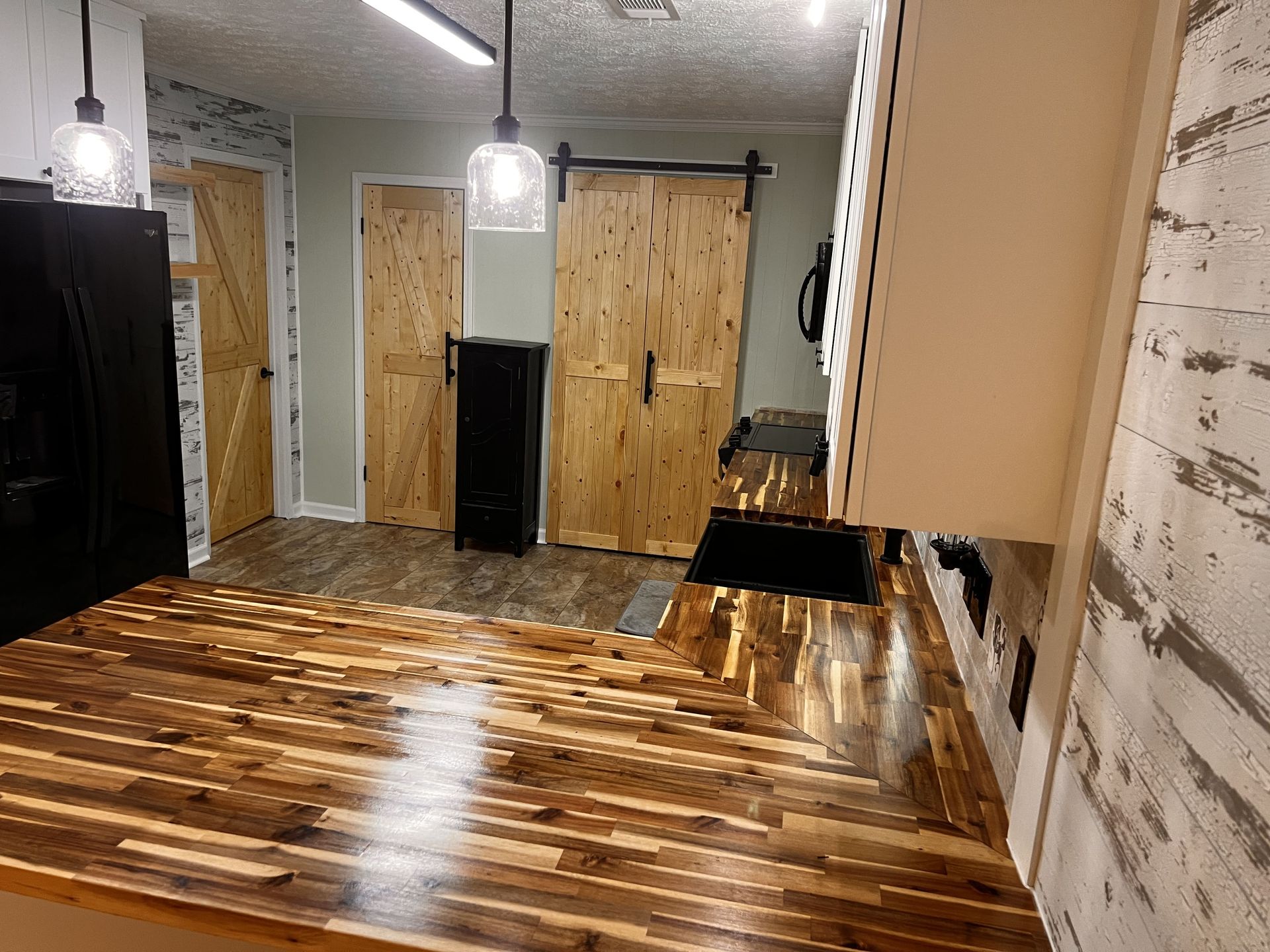 Kitchen with wood countertops, a black sink, and sliding barn doors.