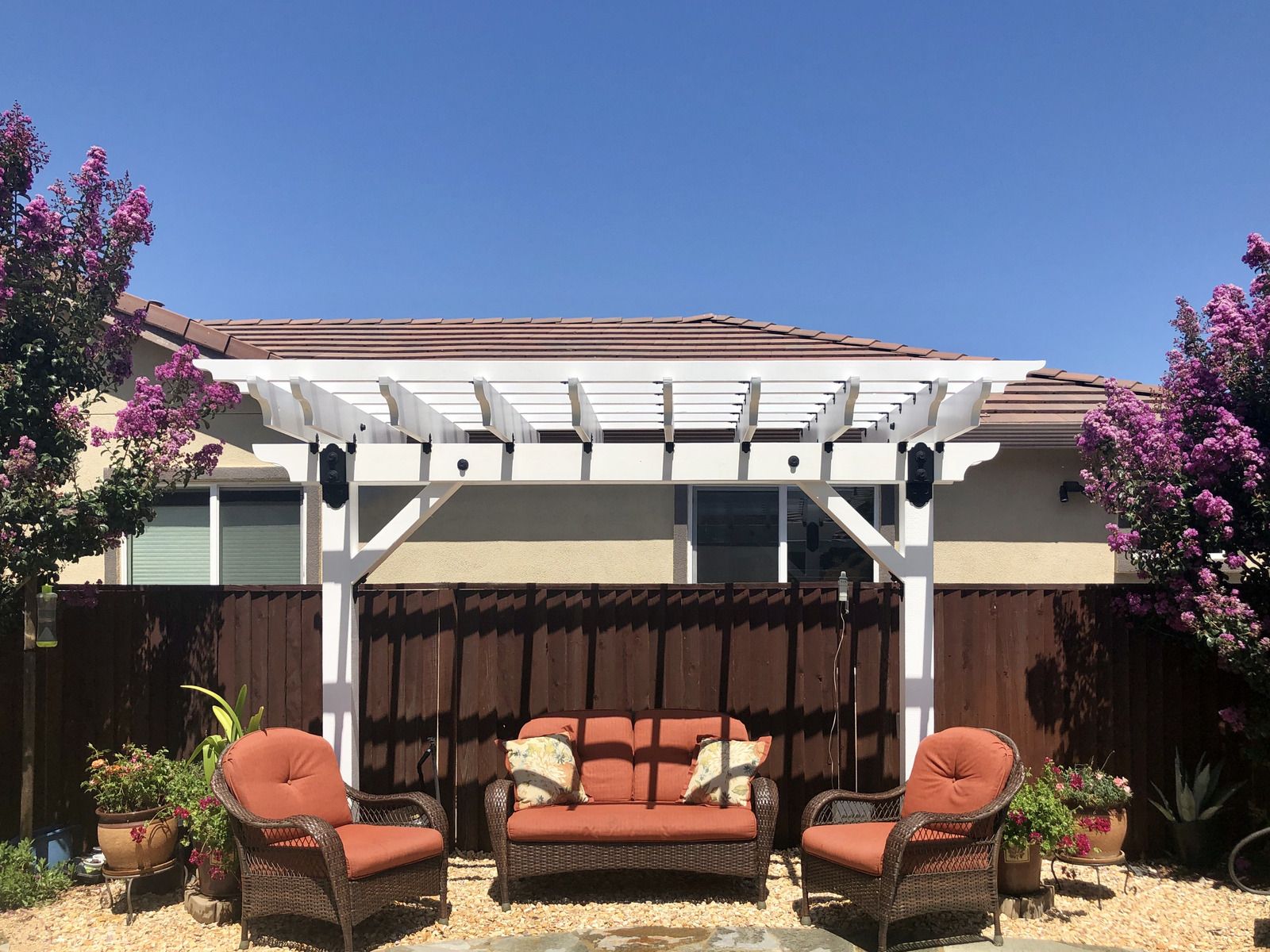 There is a pergola with a couch and chairs underneath it.